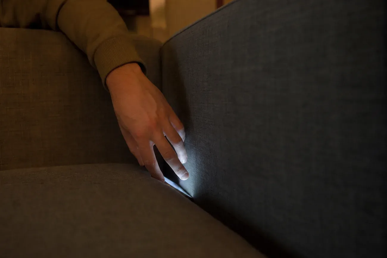 Celular en silencio entre los cojines de un sofá, con luz suave de tarde